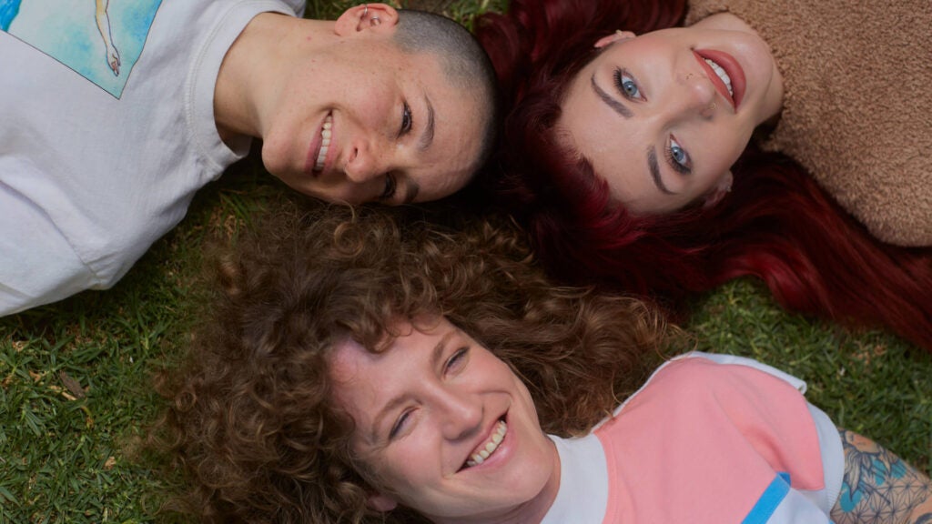 Group of three queer friends looking up at camera