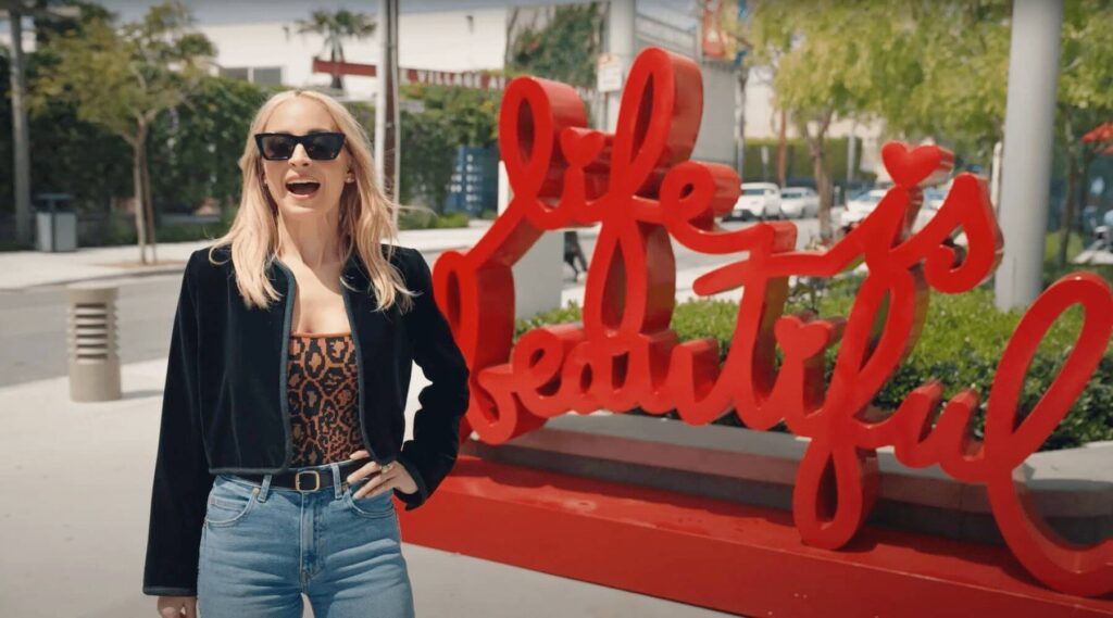 nicole richie standing in front of red cursive sign